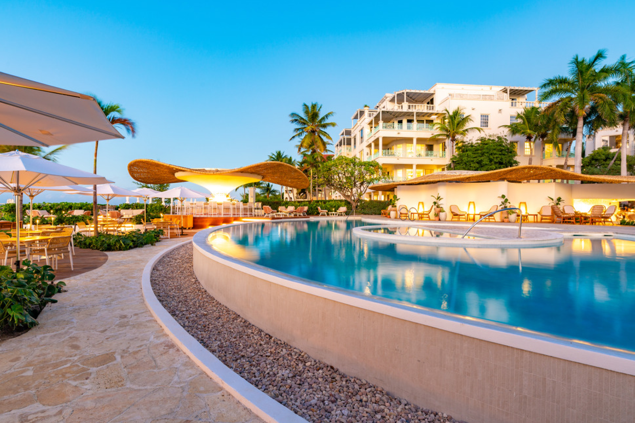 Expansive pool area at The Palms Turks and Caicos with lounge chairs and bar pavilion