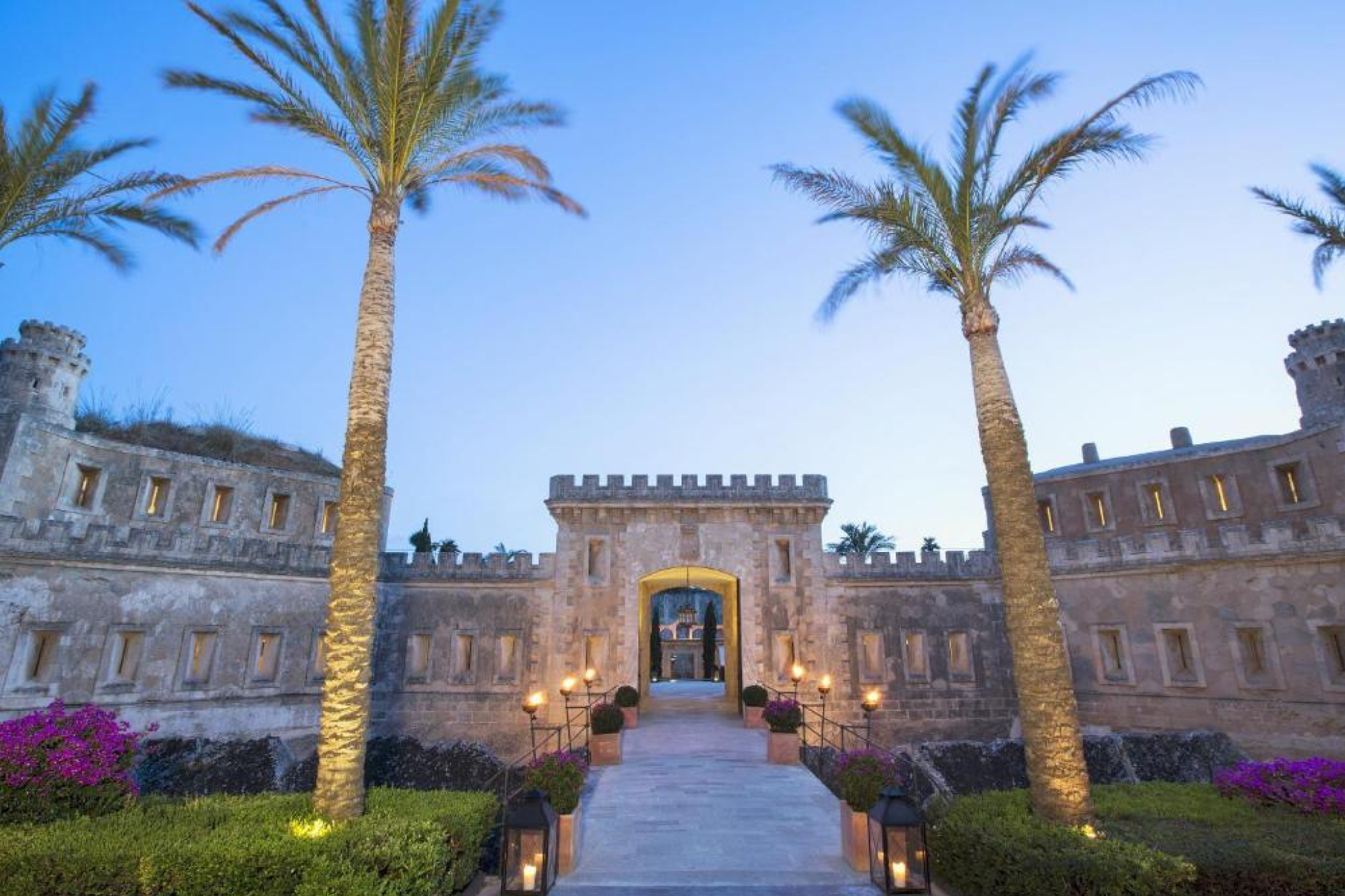 A majestic stone fortress entrance framed by palm trees at Cap Rocat in Mallorca, blending heritage architecture with seaside serenity, earning its rank among the top beach resorts in Europe in 2025.