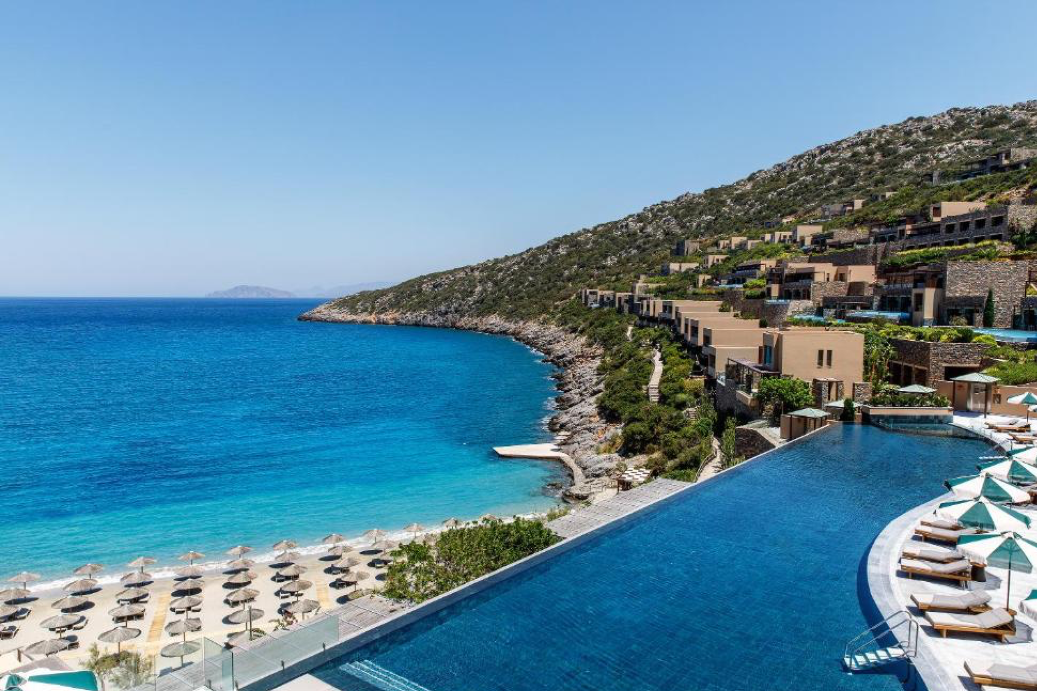 Crystal-blue waters and terraced villas built into the cliffs of Daios Cove, with an expansive infinity pool overlooking a private beach—an iconic escape recognized as one of the top beach resorts in Europe in 2025.
