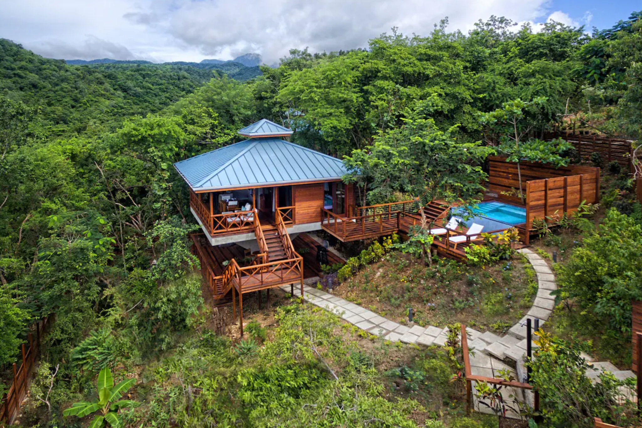 A private cliffside villa at Secret Bay surrounded by dense rainforest, wooden decks, and a secluded plunge pool overlooking lush mountains — an intimate eco-luxury hideaway that leads the list of top resorts in the Caribbean Islands in 2025.