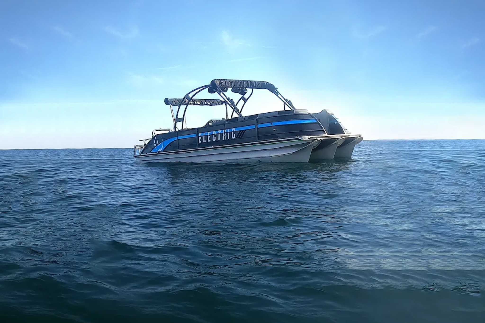 A side view of the V30 Electric Pontoon floating on calm water, highlighting its electric powertrain, multi-pontoon hull design, and balance between speed, range, and stability.