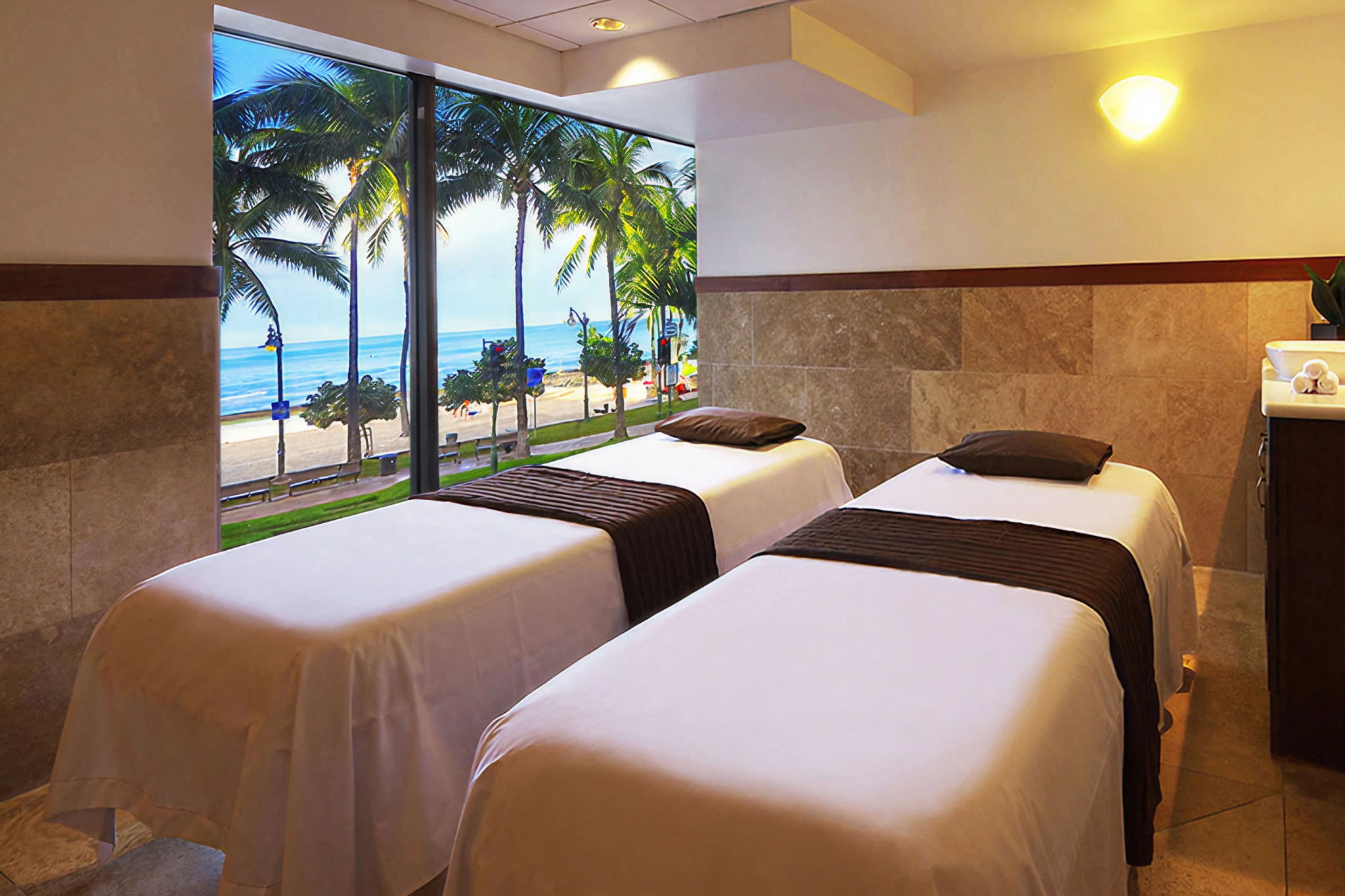 Relaxing beachfront spa room at waikiki beach marriott resort and spa with two massage tables and large windows looking out onto waikiki beach and palm trees.