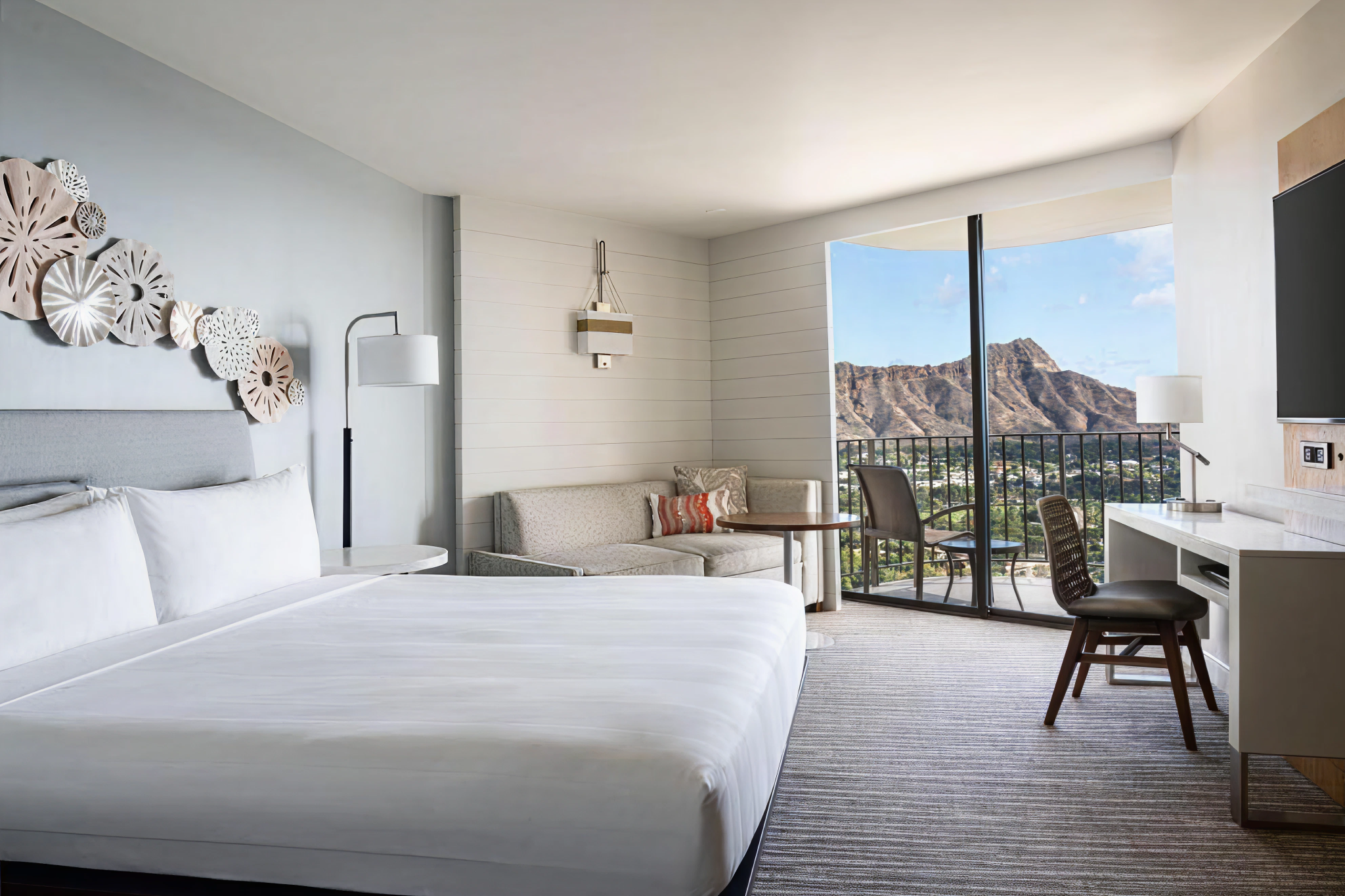 Modern guest room at waikiki beach marriott resort and spa featuring a king-size bed, cozy sitting area, and a balcony with stunning views of diamond head and waikiki.