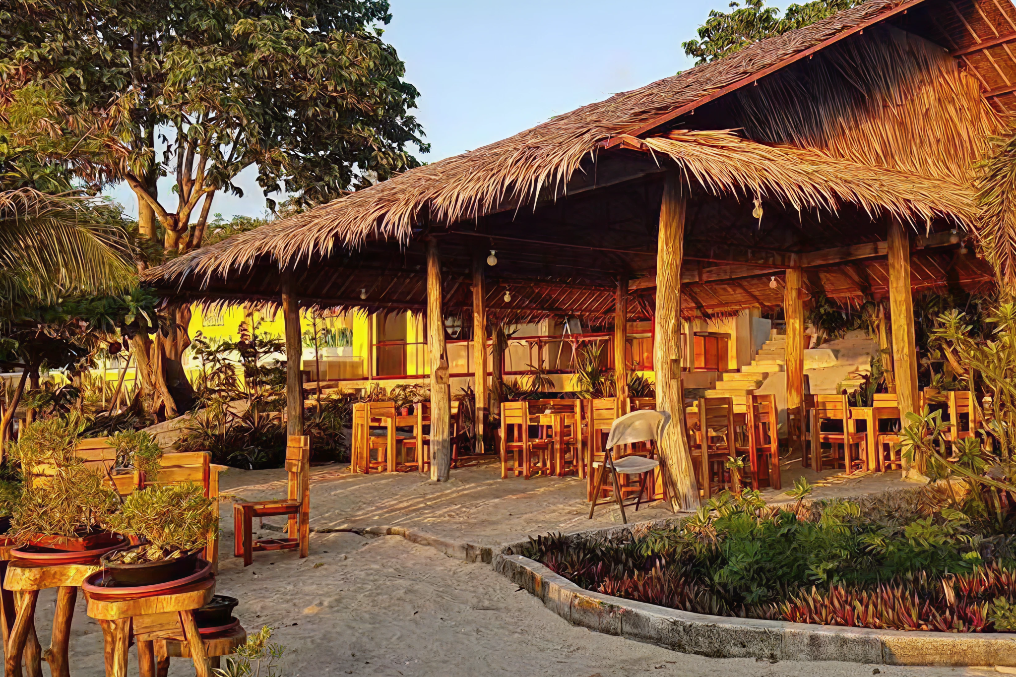 Rustic beachfront restaurant with wooden tables under a thatched roof at Bantayan Island Nature Park & Resort, glowing in the late afternoon sun — Where to Stay in Bantayan Island.