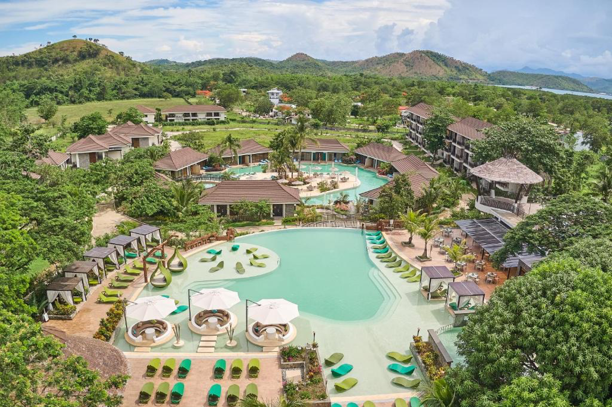 Expansive aerial shot of Tag Resort Coron, featuring its lagoon-style pool, lush greenery, and tropical architecture — a family-friendly haven among the best choices for Where to Stay in Coron.