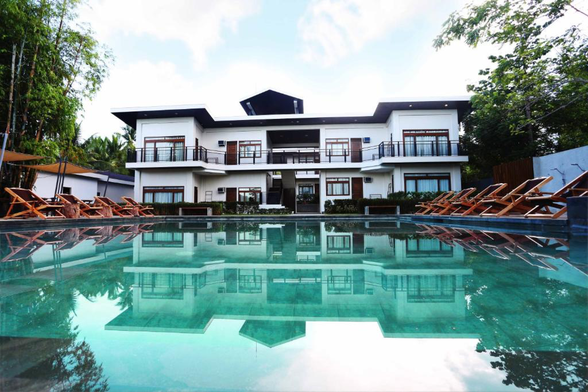 A serene pool view of The Funny Lion Coron, showcasing its modern rooms, wooden accents, and relaxed boutique atmosphere — ideal for travelers searching Where to Stay in Coron.