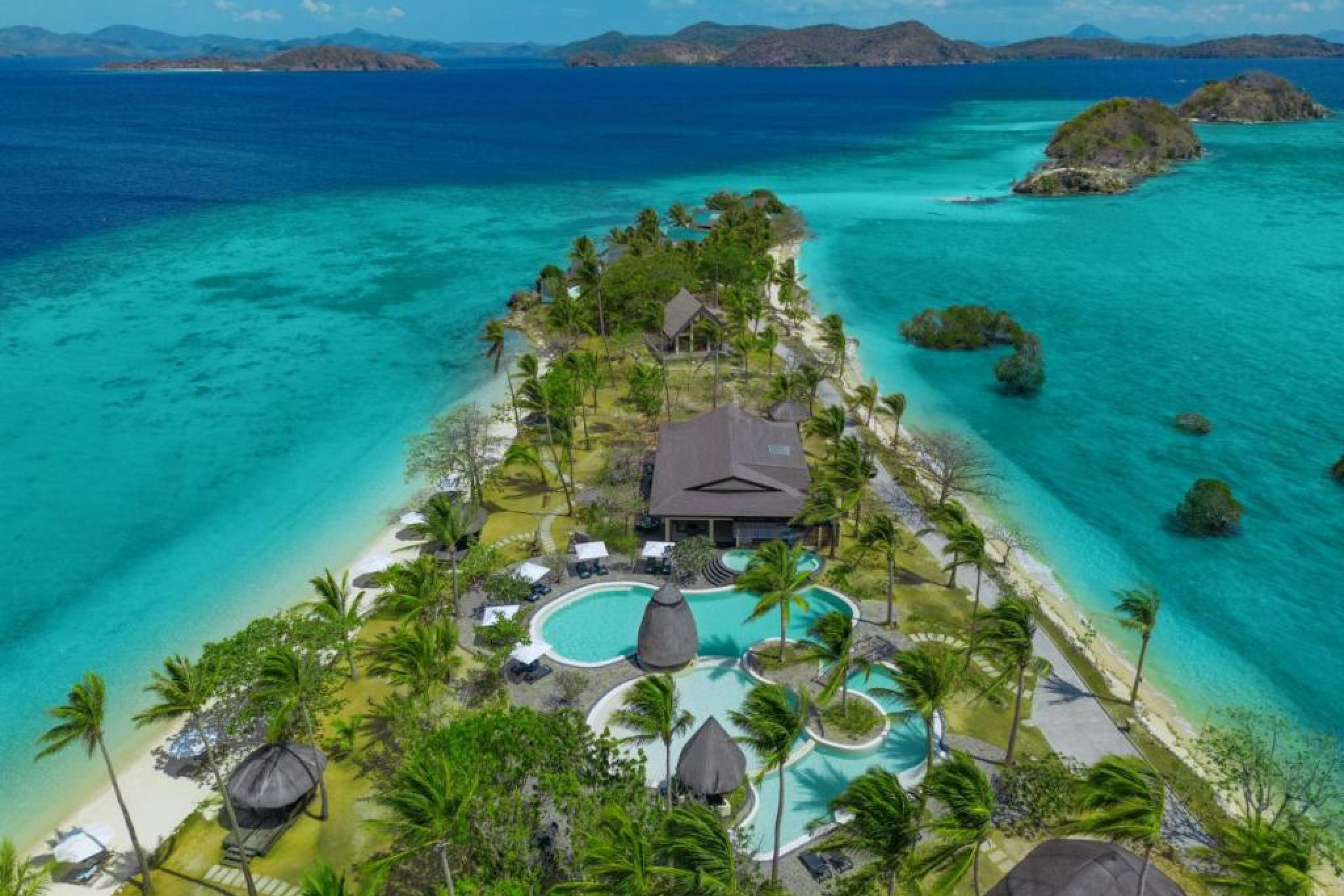 Overhead view of Two Seasons Coron Island Resort & Spa, with its beachfront villas, palm-lined pools, and crystal-clear lagoon — an exclusive escape for Where to Stay in Coron luxury seekers.