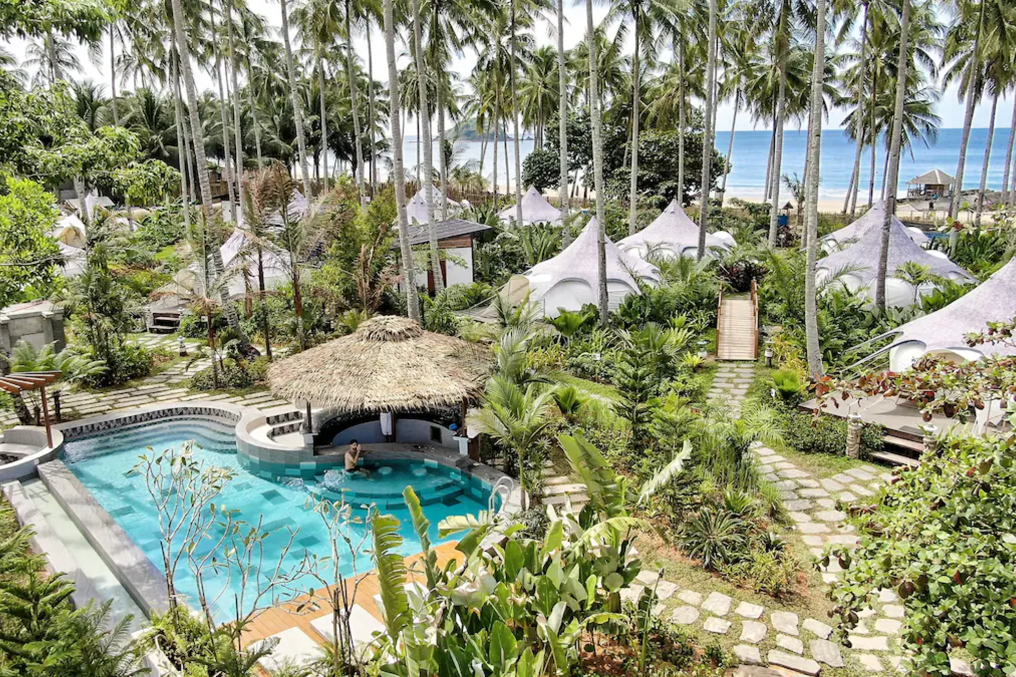 Tropical glamping tents and pool under palm trees — where to stay in El Nido, Palawan.