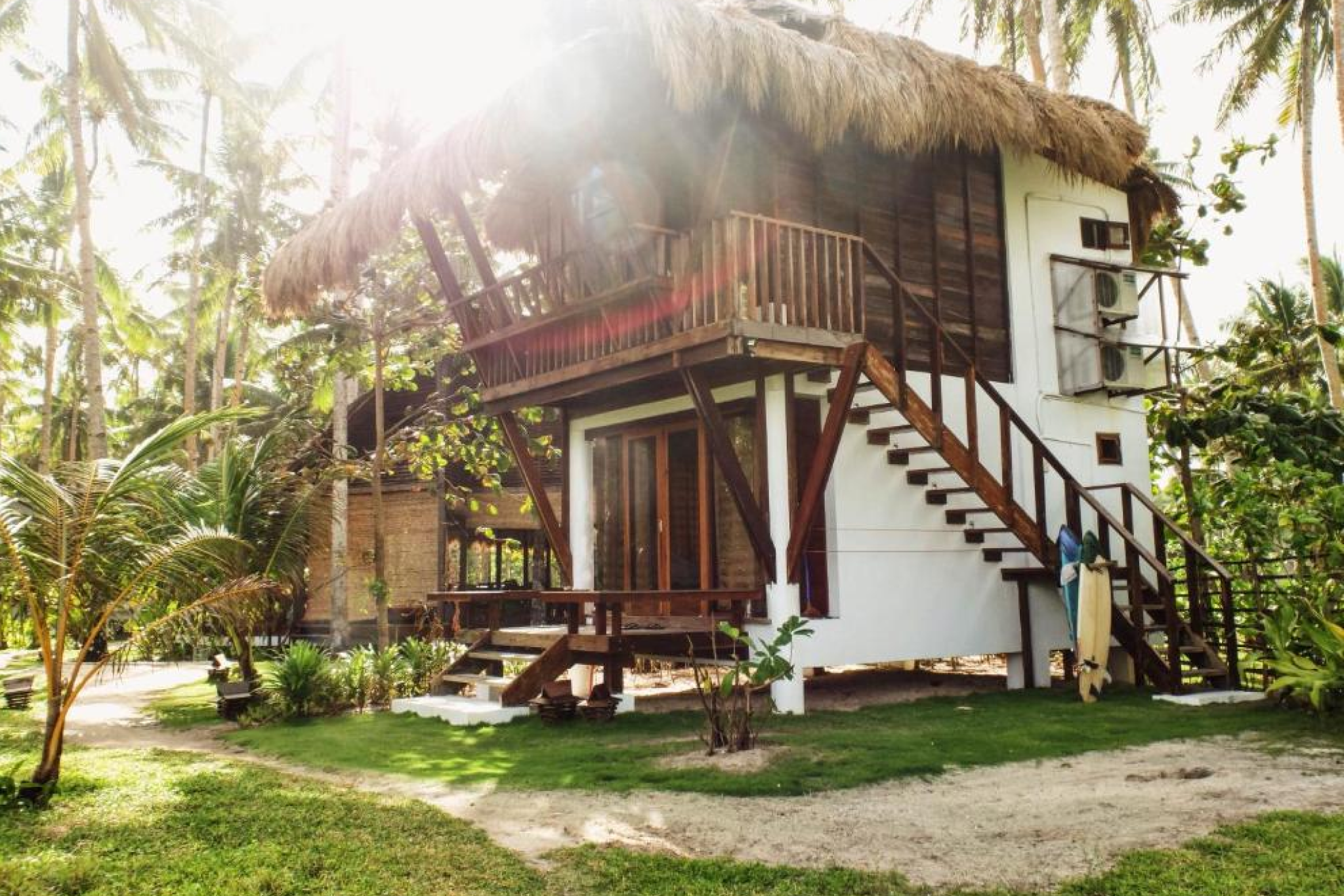 Thatched two-story surfside villa surrounded by palms — Bravo Beach Resort, Where to Stay in Siargao.