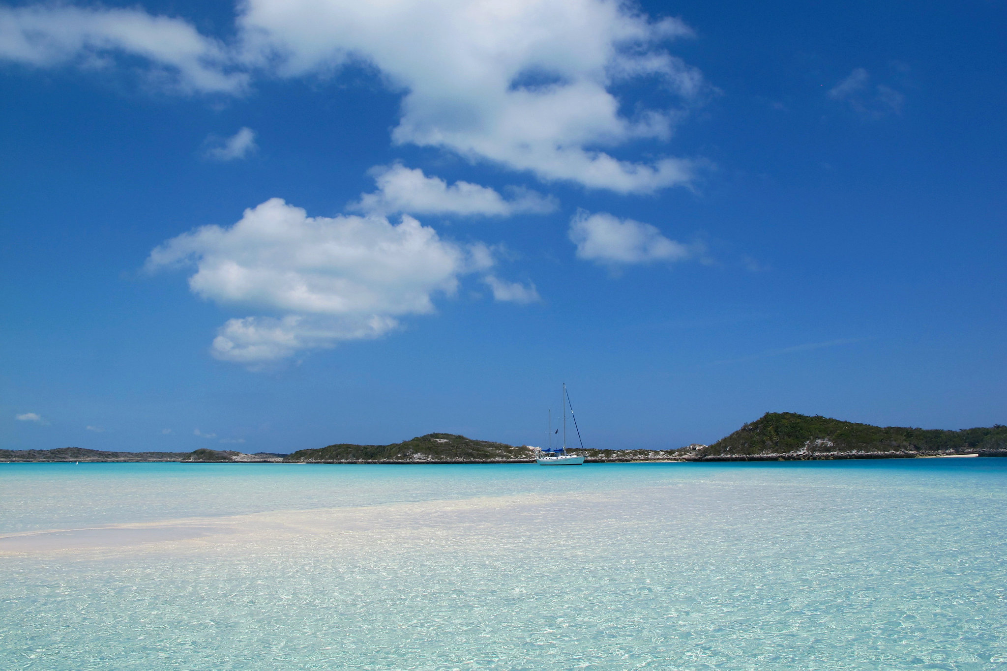 Rocky coastline and green vegetation on a mid-sized Bahamian island surrounded by clear ocean waters, a valuable and exclusive billionaire island owned by Aga Khan IV.