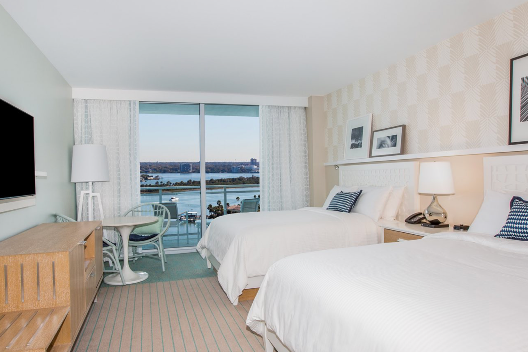 Contemporary guest room at Wyndham Grand Clearwater Beach featuring two queen beds, minimalist decor, and a marina-facing balcony.