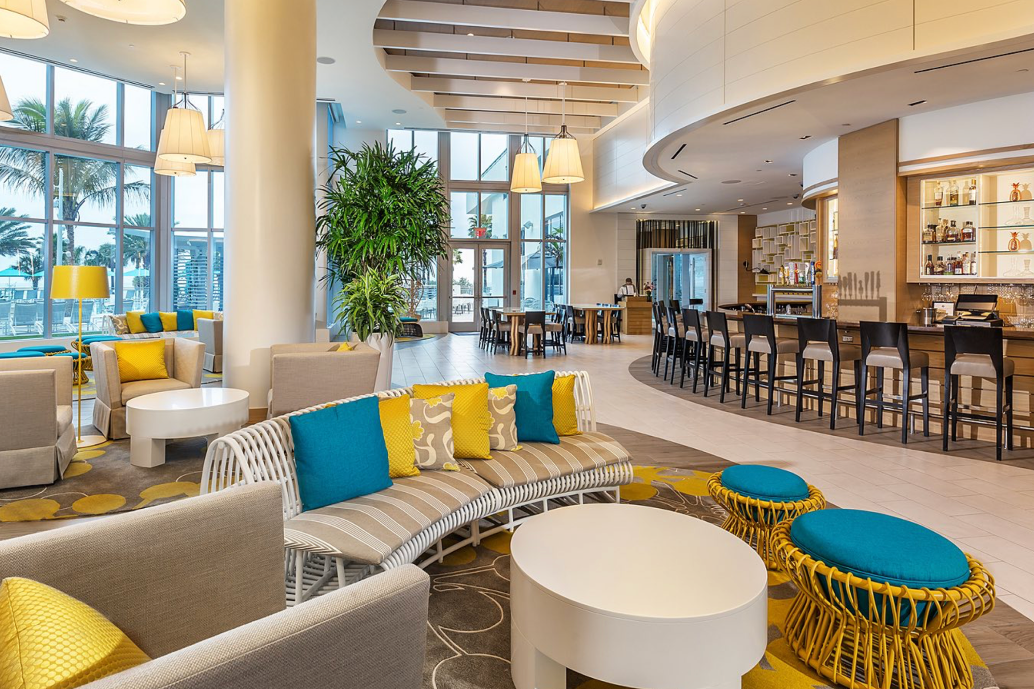 Bright and modern lobby at Wyndham Grand Clearwater Beach with vibrant seating, high ceilings, and an ocean-facing cocktail bar.