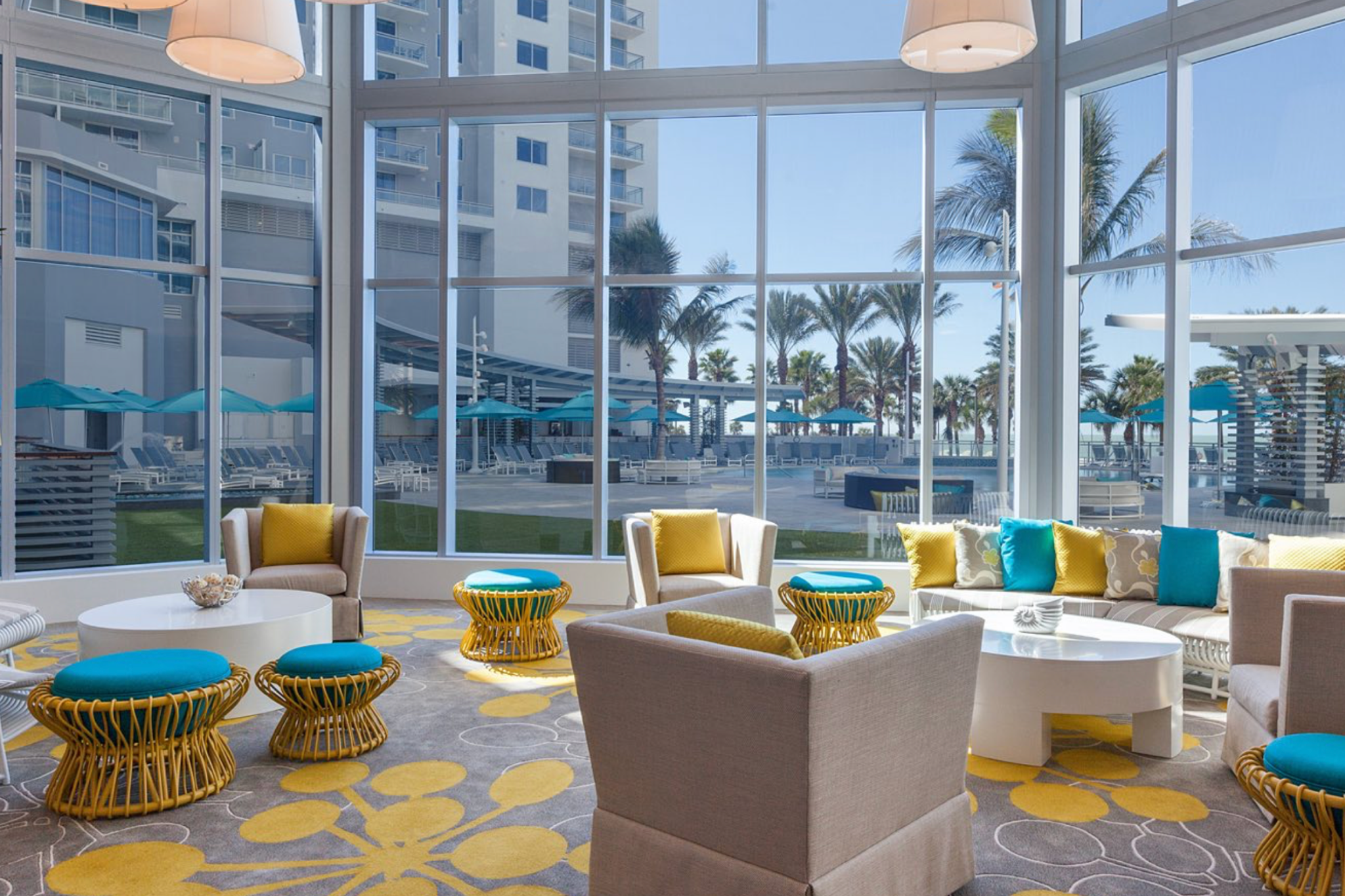 Stylish indoor lounge at Wyndham Grand Clearwater Beach with large windows overlooking the pool deck and palm-lined beachfront.