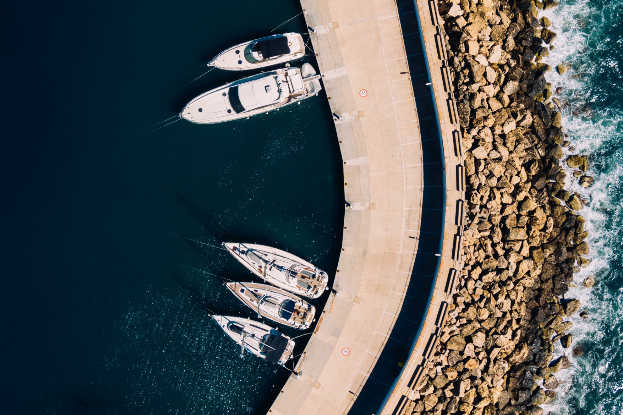 Aerial view of yachts and boats docked at a marina, reinforcing the visual contrast in the yacht vs boat discussion.